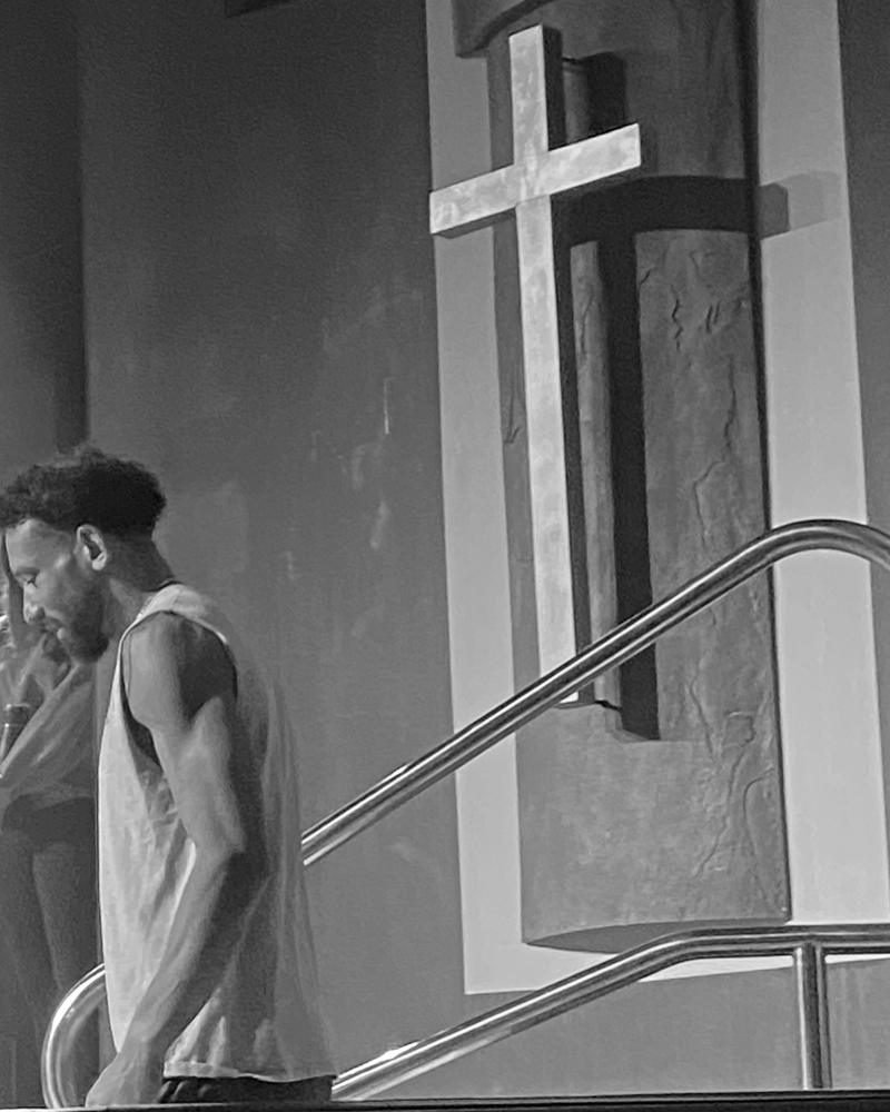Eddie J. Smith III walking down the baptistry steps, a cross on the wall behind him